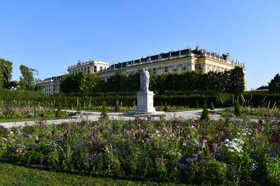 bepflanzte Beete bei der Kaiserfigur mit Schloss Schönbrunn