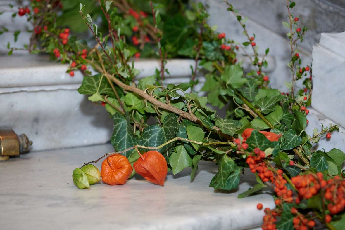 Nahaufnahme des Blumenschmucks auf der Stiege bestehend aus Physalis, Vogelbeere und Efeu.