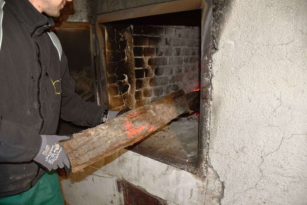 Gärtner schiebt Brennholz in den offenen Ofen