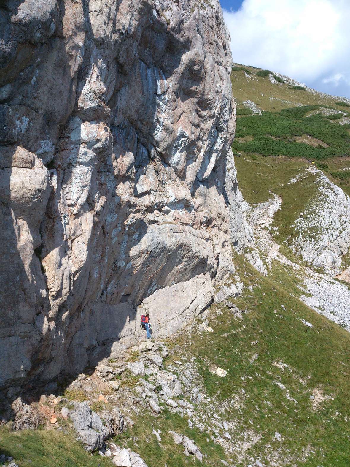 Ein Mensch geht unterhalb einer Steilwand entlang.