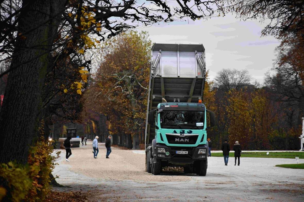 zu sehen ist ein Lastwagen, der Kies auf Schotterwege kippt